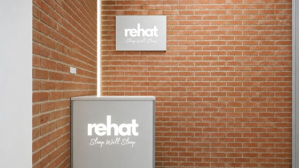 A brick wall with a sign that reads 'rehat Sleep Well Sleep' and a white box with the same logo. - Rehat at Alamanda 7 Syariah Guest House (Bandung)