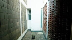 A narrow alleyway with a potted plant, a window, and a brick wall. - Rehat at Alamanda 7 Syariah Guest House (Bandung)