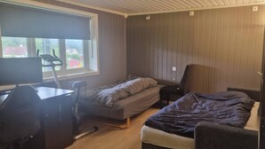 Une pièce de taille modeste comprenant un lit, un bureau avec une chaise, une fenêtre donnant sur un paysage agréable et une porte.