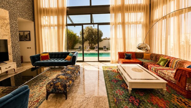 A spacious living room with a large window, a pool view, and a modern interior design. - Villa Solis - Elegant Villa with Private Pool (Marsa)