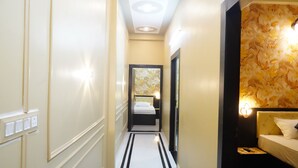 Un couloir d’hôtel avec un lit, une salle de bain et un miroir.