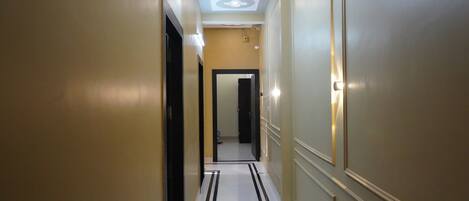 A hallway with a polished floor, recessed lighting, and a door at the end.