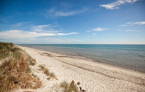 A beach with sand and sparse vegetation, a clear sky, and calm water. - Awesome home in Sæby with sauna (Sæby)