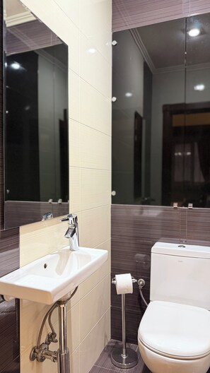 Een moderne badkamer met een wastafel, toilet en spiegel.