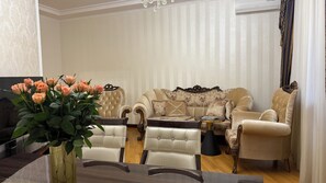 Een woonkamer met een bank, fauteuils, een salontafel en een bloemenvaas.