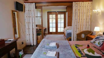 A hotel room with a bed, a desk, a chair, a TV, and a bathroom visible through a door.