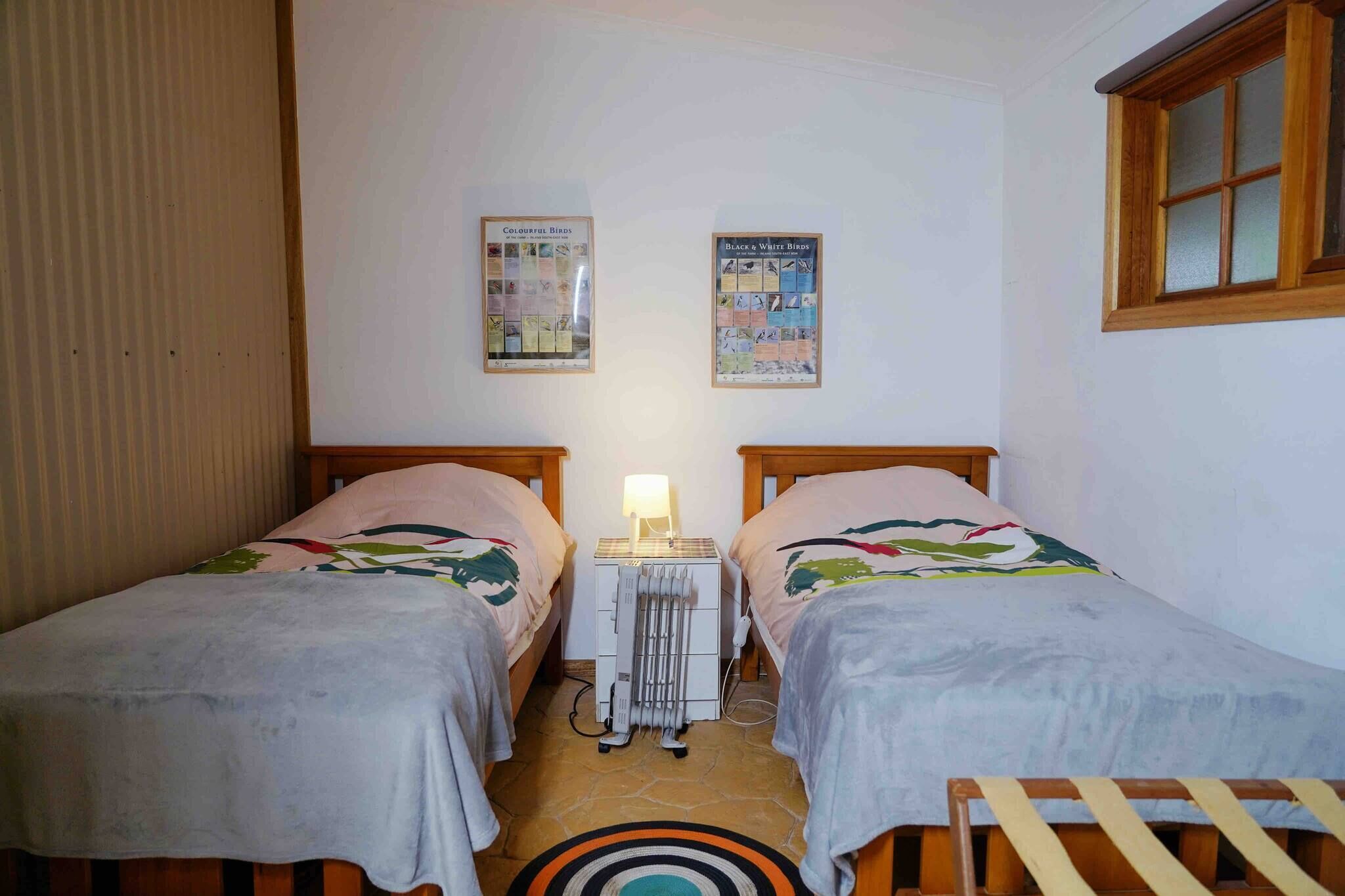 A small room with two beds, a radiator, and two wall posters.