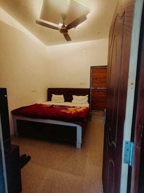 Une chambre à coucher avec un lit, un ventilateur de plafond et une armoire en bois.