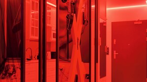 Ein Zimmer in Rot, mit einer Tür, einem Spiegel und einem Fenster.