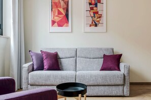 A grey sofa with two purple cushions, a black tray on a wooden stand, and abstract art on the wall. - Milan-Bergonzoli-Hugo - 1 apartment BDR (Milano)