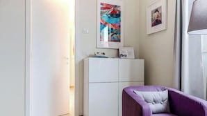 A modern room with a white wardrobe, a purple sofa, and a framed abstract painting on the wall. - Milan-Bergonzoli-Hugo - 1 apartment BDR (Milano)