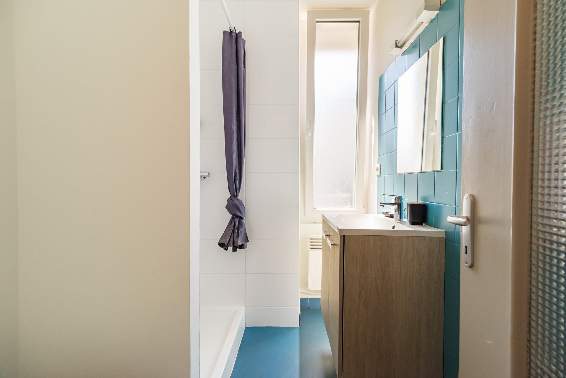 A narrow hallway with a bathroom featuring a sink, mirror, and towel rack.
