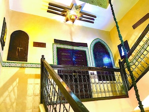 A staircase with ornate metal railings, a star-shaped light fixture, and a door with a decorative frame.