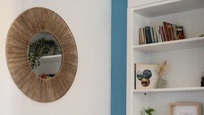A room with a round mirror, a white bookshelf, and a blue accent wall. - Casa Vacanze Ca Zigoela (La Spezia)