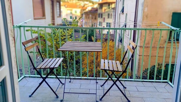 A balcony with a table and two chairs, surrounded by a green metal railing. - Casa Vacanze Ca Zigoela (La Spezia)