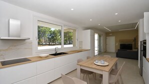 A modern kitchen with a large window, a dining area with a wooden table, and a built-in oven. - Villa in Augusta with 3 bedrooms sleeps 8 (Augusta)