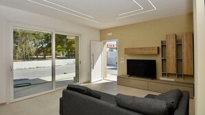 A modern living room with a grey sofa, a flat-screen TV, and a wooden shelving unit. - Villa in Augusta with 3 bedrooms sleeps 8 (Augusta)