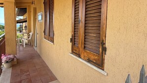 Un corridoio con persiane di legno, pavimento piastrellato e vista sul mare.