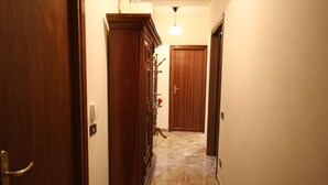 Un corridoio con porte in legno, pavimento in marmo e lampadario.