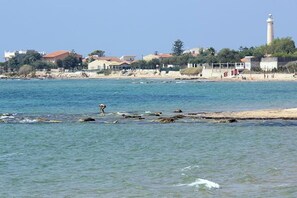 Eine Küstenlandschaft mit einem Leuchtturm, Strand und Wohnhäusern.
