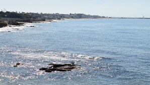 A coastal view with a clear sky, calm sea, and a distant shoreline with buildings. - Le Vele della Contea (Marina Di Modica)