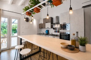 Una cocina moderna con una isla grande, taburetes de bar y plantas colgantes.