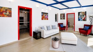Una sala de estar moderna con un sofá blanco, sillas rojas y obras de arte en las paredes.