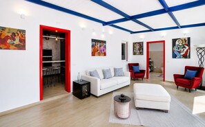 A modern living room with a white sofa, red chairs, and artwork on the walls. - Villa Didymos by Geco Vacation Rentals (Chiaramonte Gulfi)