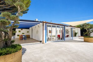 Une maison moderne dotée d’un patio couvert, d’un coin repas et d’une véranda.