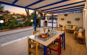 Une terrasse extérieure équipée d’une table à manger, de chaises et d’un barbecue encastré.