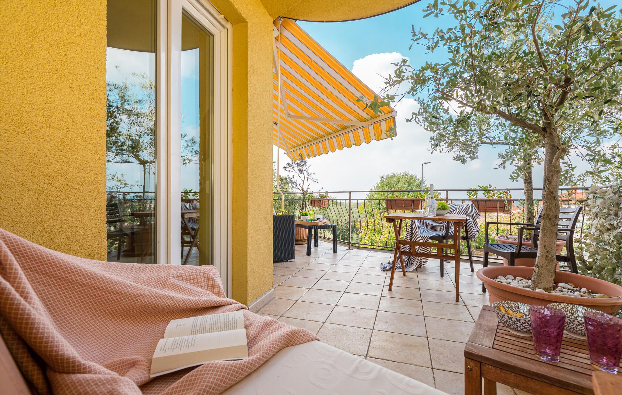 A balcony with a sofa, a table, and potted plants.