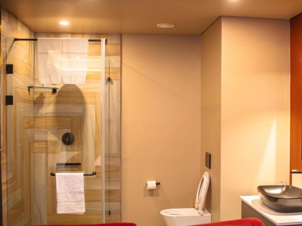 A bathroom with a glass shower enclosure, a toilet, and a sink with a basin.
