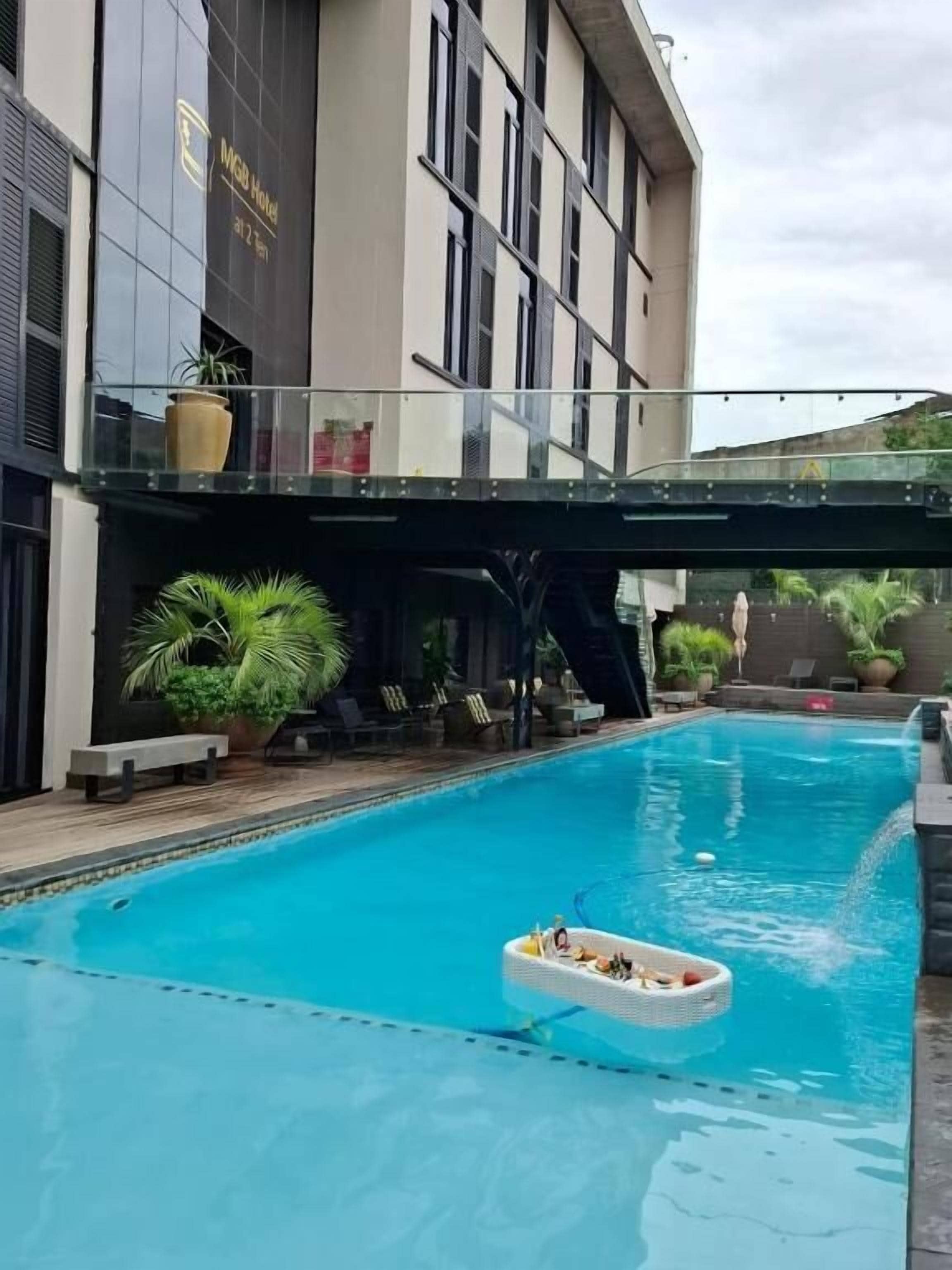 Une piscine dotée d’un pont de verre, de chaises longues et de plantes en pot.