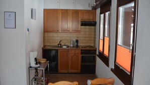 Eine Küche mit Holzausstattung, Spüle, Herd und einem Fenster mit Jalousien.