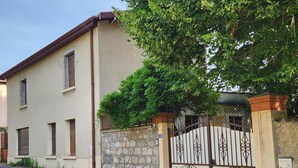 Un edificio su due piani con un muro in pietra e un cancello in metallo.
