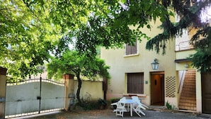 Un cortile con tavolo e sedie, un cancello e un edificio con una porta e una finestra.