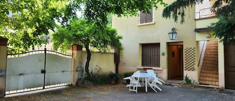 Un patio con una mesa, sillas, una puerta y un edificio con ventana.