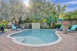 Um quintal com piscina, espreguiçadeiras e cerca de madeira.