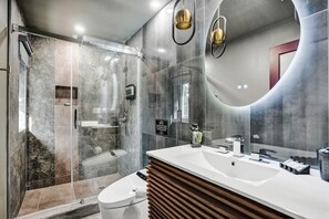 Une salle de bain moderne avec une douche à parois de verre, un lavabo blanc et un grand miroir.