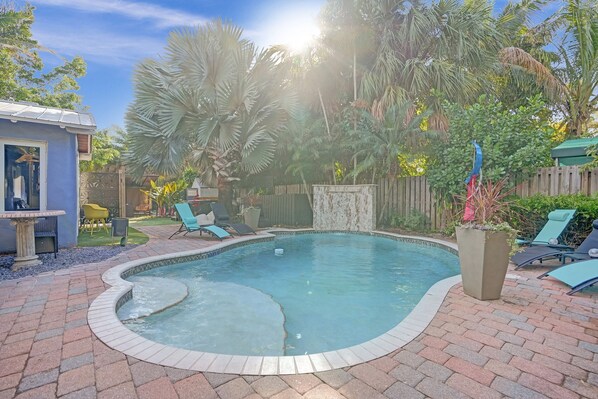 Un jardin avec une piscine, du mobilier de jardin et une clôture en bois.