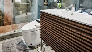 A modern bathroom with a glass-enclosed shower, a white toilet, a wooden vanity, and a large mirror.