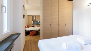Un dormitorio moderno con cama, armario y vistas hacia una zona de cocina.