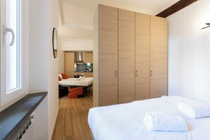 Ein modernes Schlafzimmer mit Bett, Kleiderschrank und Blick in einen Küchenbereich.