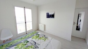 Een slaapkamer met een bed, een radiator, een deur en een raam.
