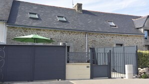 A stone building with a grey roof, a gated entrance, and a small window.
