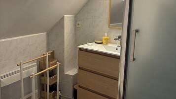 Een moderne badkamer met dakraam, toilet, houten wastafelmeubel en een douchecabine van glas.