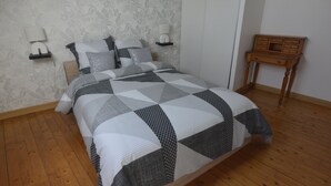 A neatly made bed with a geometric patterned bedspread, two bedside lamps, a small wooden nightstand, and a nightstand lamp.