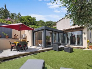 A modern outdoor patio with a glass enclosure, outdoor furniture, and a red umbrella. - Hameau de Croisette Plage by Interhome (Sainte Maxime)