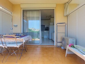 A patio with a table and chairs, a sliding glass door leading to a kitchen, and a radiator on the right. - Les Coteaux de la Nartelle by Interhome (Sainte Maxime)