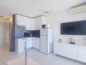 Une cuisine moderne avec des meubles blancs, un four à micro-ondes encastré et un réfrigérateur.